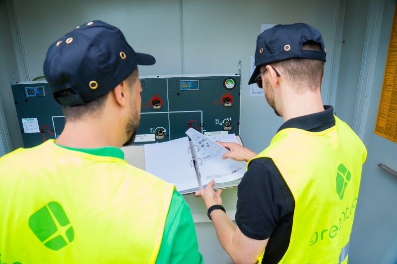 Zwei greentech-Ingenieure prüfen Schaltanlage und Dokumentation bei der Abnahmebegleitung einer Energieanlage