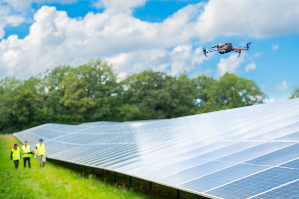 Eine Drohne fliegt bei einer Inspektion über einen Solarpark für eine effiziente Drohnen-Thermografie zur Sicherung der Anlagen-Erträge.