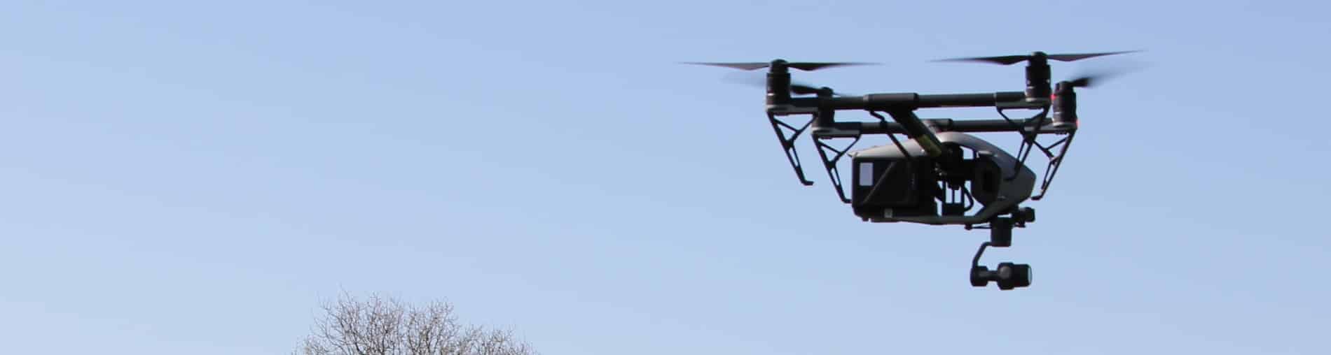 Professionelle Drohne im Flug für die Flächen- und Routenanalyse zur Planung von PV-, BESS- oder UW-Projekten.