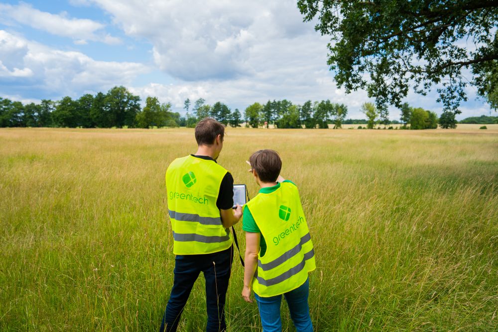 Two greentech experts inspecting an open-field site to analyze access routes and locations.