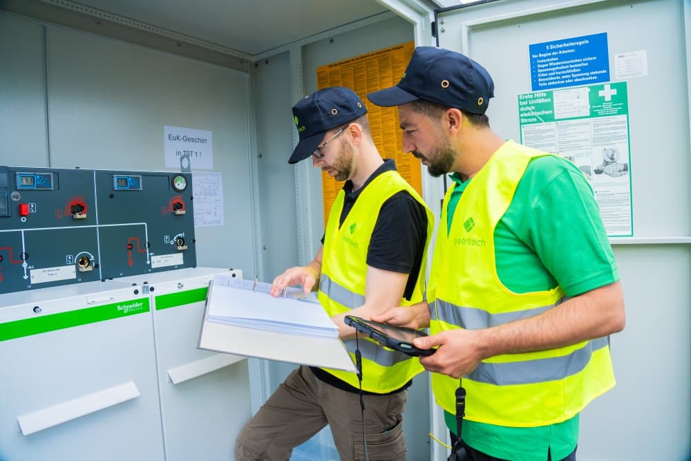 Zwei PV-Spezialisten von greentech nutzen ihr technisches Know-how für die normgerechte Elektroplanung an einer Schaltanlage.